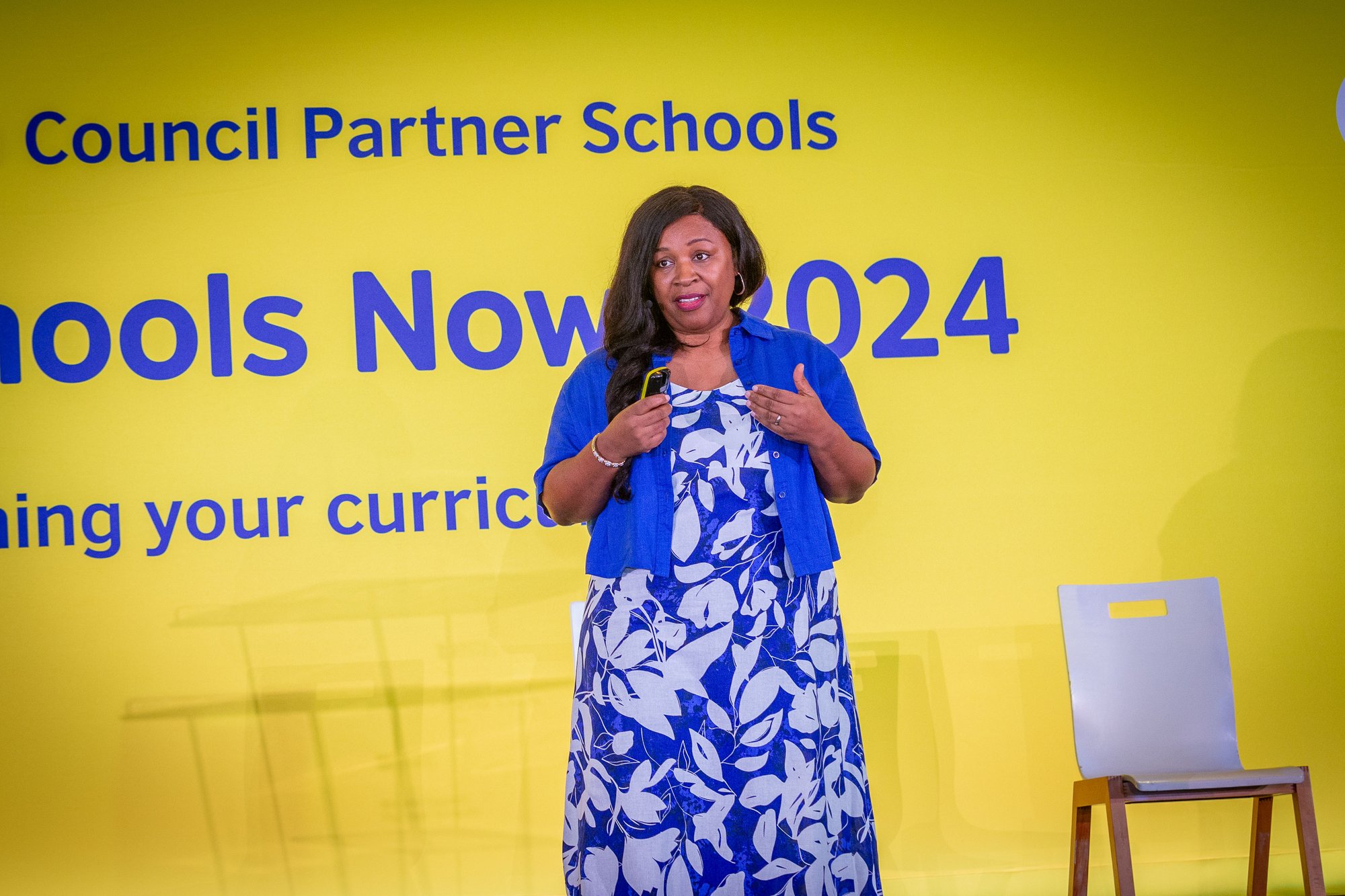 Female Schools Now! keynote speaker in front of main yellow  backdrop on stage