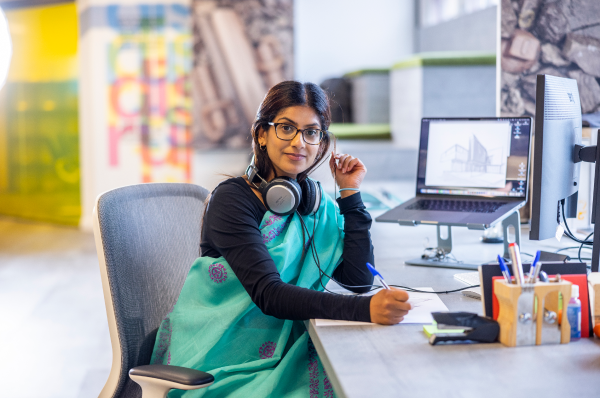 Young Indian woman sitting at a desk wearing headphones