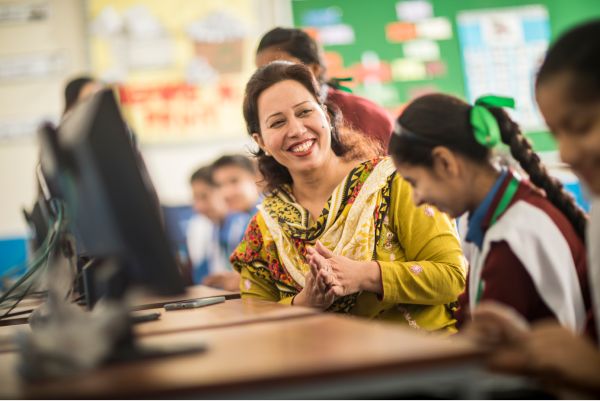 Teacher talking to a row of students sitting in a computer hub