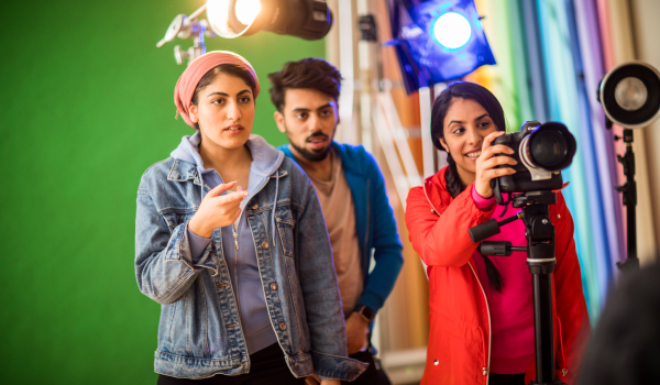 Three flm students instructing and capturing photos in a studio