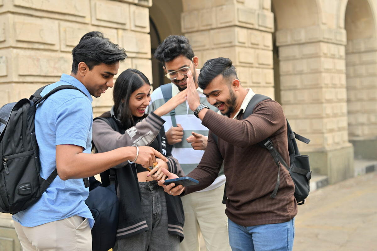 Four students checking exam results on a phone